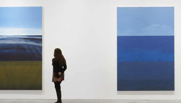 A person looks at two paintings by Byron Kim.