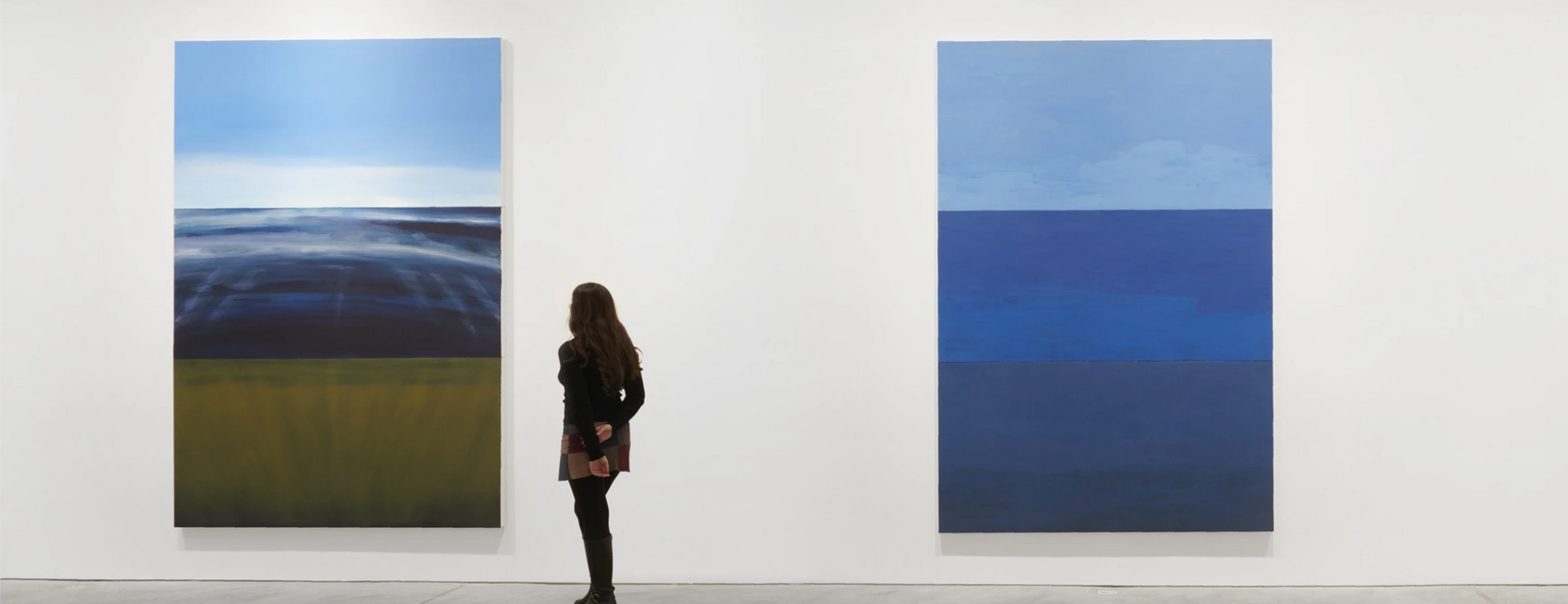 A person looks at two paintings by Byron Kim.